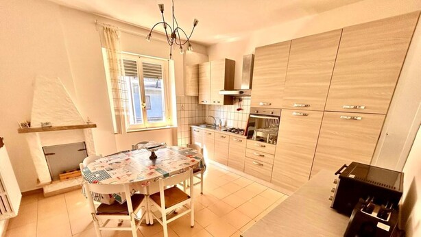 Cocina compacta con una mesa de comedor, armarios y horno empotrado.