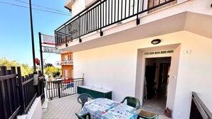 Un patio con una mesa y sillas, un balcón y un edificio al fondo.