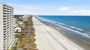 A beachfront hotel with multiple floors, a pool, and a boardwalk leading to the beach. - White Lotus Beach Retreat w Pool and Ocean Peek (North Myrtle Beach)