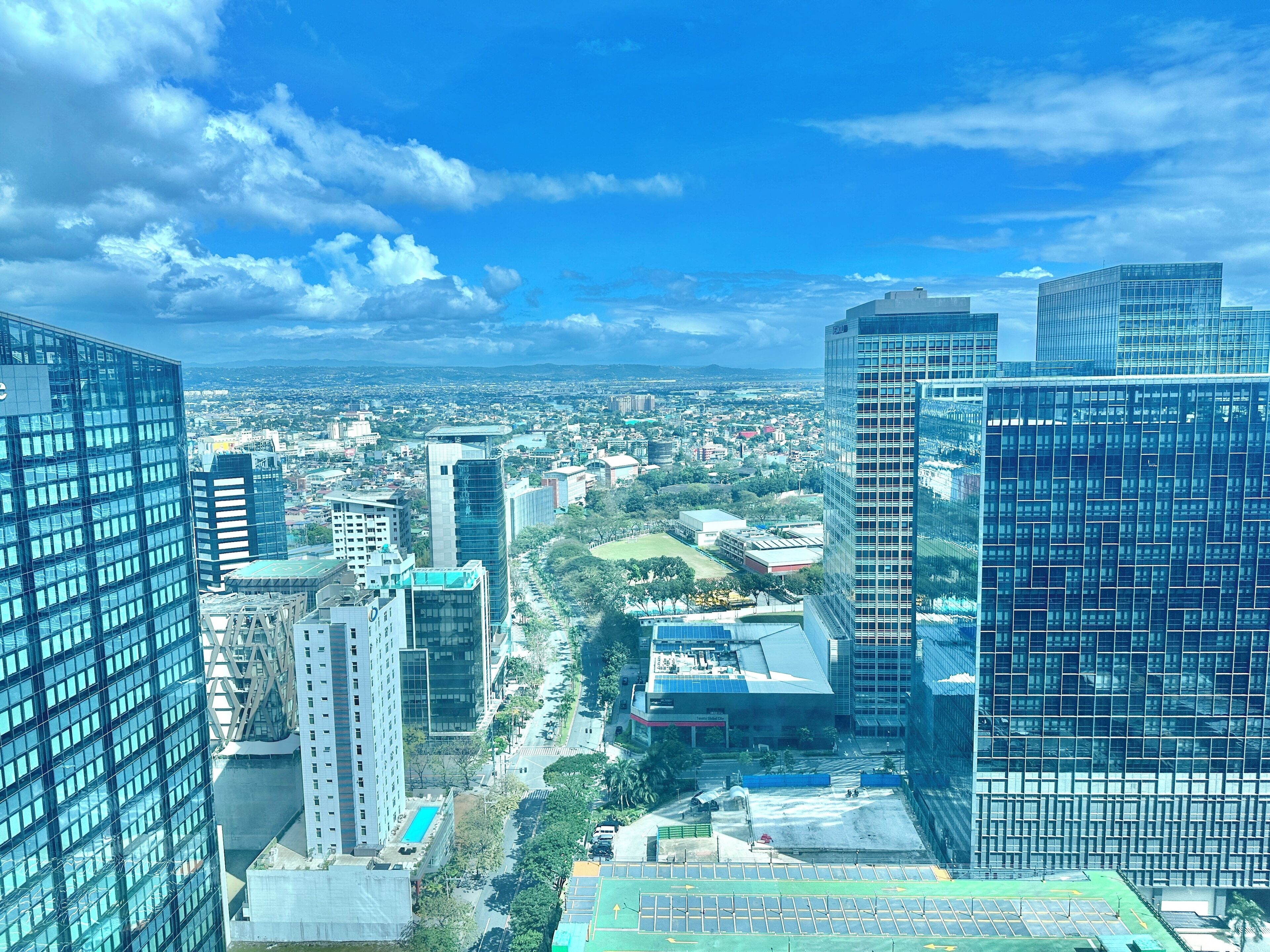 A cityscape with modern high-rise buildings, a clear sky, and a distant view of a city.