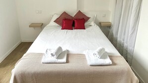 Hotelkamer met een bed, twee kussens, twee nachtkastjes, een lijst aan de muur, en een raam met gordijnen.