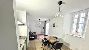 Een modern appartement met een eetgedeelte, een woonkamer met een bank en een keuken.