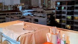 Un espace dédié à la lessive, comprenant un lave-linge, une table abritée et divers produits de toilette.
