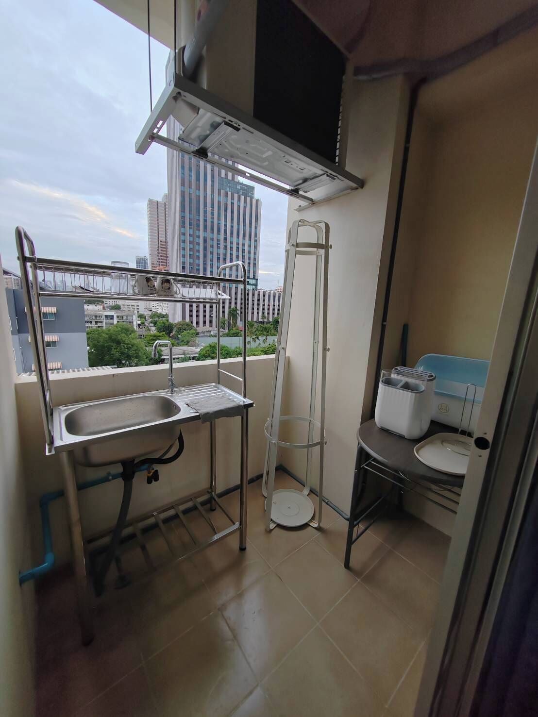 A compact balcony with a sink, a small table, a ladder, and a compact kitchenette.