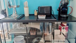 Un comptoir de cuisine avec une machine à café, une bouilloire et un paquet de capsules de café.