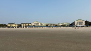 A beachfront hotel with multiple buildings, a sandy beach, and blue umbrellas. - Marriott Surfwatch - OCEANFRONT (Hilton Head Island)