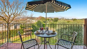 A balcony with a table, chairs, and an umbrella. - Cosy House Serena- Park & Shared Pool (Puegnago del Garda)