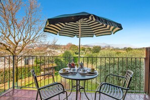 Ein Balkon mit Tisch, Stühlen und Sonnenschirm.