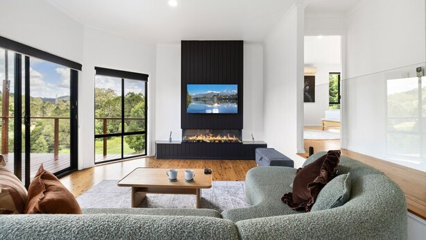 Ein modernes Wohnzimmer mit Kamin, großen Fenstern und einer gemütlichen Sitzecke.