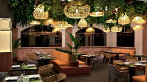 En restaurang med flera bord och stolar, hängande lampor av rotting och en vägg av tegelsten.