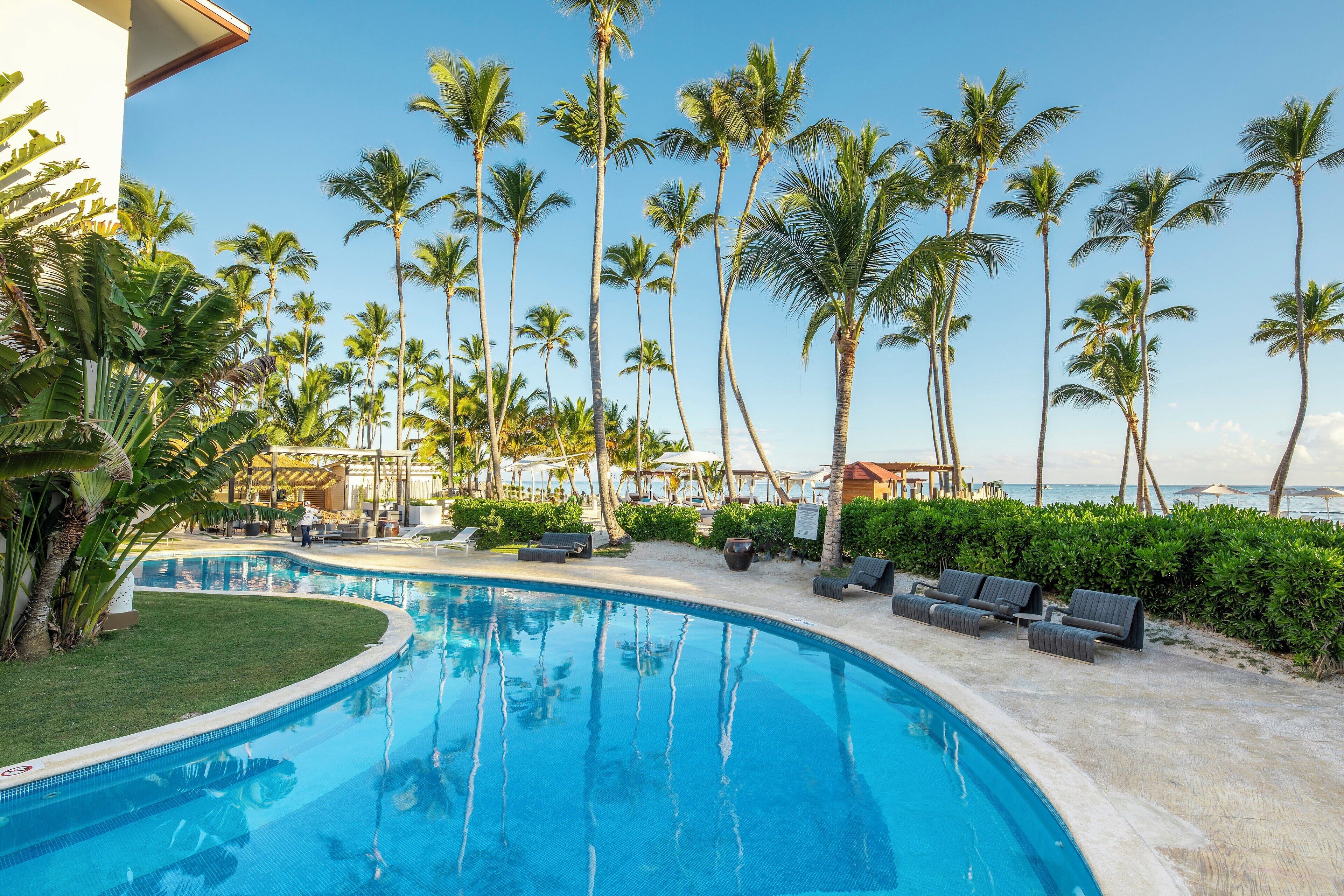 A pool area with lounge chairs and palm trees.