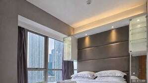Ein modernes Hotelzimmer mit einem großen Bett, einem Glastisch und Blick auf die Stadt.