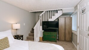 A bedroom with a bed, a TV, a staircase, and a wardrobe. - Updated 3 Bedroom Charmer (Kelso)