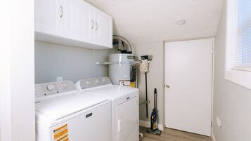 A laundry room with two front-loading washing machines, a dryer, and a water heater.