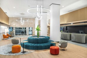 A modern lobby with a circular seating area, a reception desk, and a fireplace. - Danubius Hungaria City Centre (Budapest)