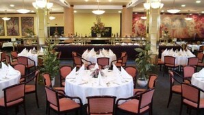 Une salle à manger élégante, avec des tables rondes disposées pour accueillir plusieurs convives, agrémentée de nappes blanches et de chaises à revêtement rouge.