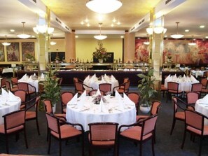 A formal dining area with round tables set for multiple guests, featuring white tablecloths and red upholstered chairs. - Danubius Hungaria City Centre (Budapest)