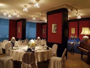 Une salle à manger élégante, avec des tables rondes, des chaises blanches et des lustres.