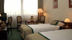 Une chambre d’hôtel avec deux lits, un bureau avec une lampe, une chaise et un téléviseur.