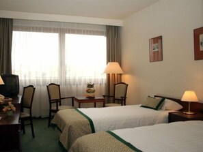 A hotel room with two beds, a desk with a lamp, a chair, and a television. - Danubius Hungaria City Centre (Budapest)