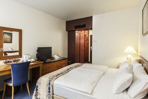 Une chambre d’hôtel avec un lit, un bureau avec un ordinateur, une chaise, une lampe et une porte.