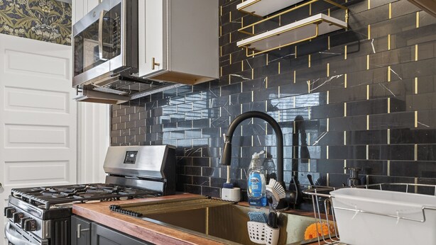 A kitchen with a stove, oven, and modern backsplash. - Classic Heritage Hill Remodeled 2 Bedroom with Bold and Warm Colors (Grand Rapids)