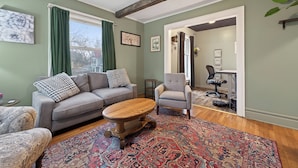 A living room with a sofa, armchair, coffee table, and patterned rug. - Classic Heritage Hill Remodeled 2 Bedroom with Bold and Warm Colors (Grand Rapids)