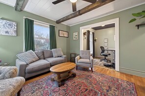 A living room with a sofa, armchair, coffee table, and patterned rug. - Classic Heritage Hill Remodeled 2 Bedroom with Bold and Warm Colors (Grand Rapids)