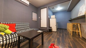 A compact living space with a sofa, a small table, a refrigerator, and a microwave. - Cozy Modern Apartment | Walk to Tanimachi & Easy Access to Namba & Osaka Castle (Osaka-cty,Tennoujiku,Shimizudani-chou)