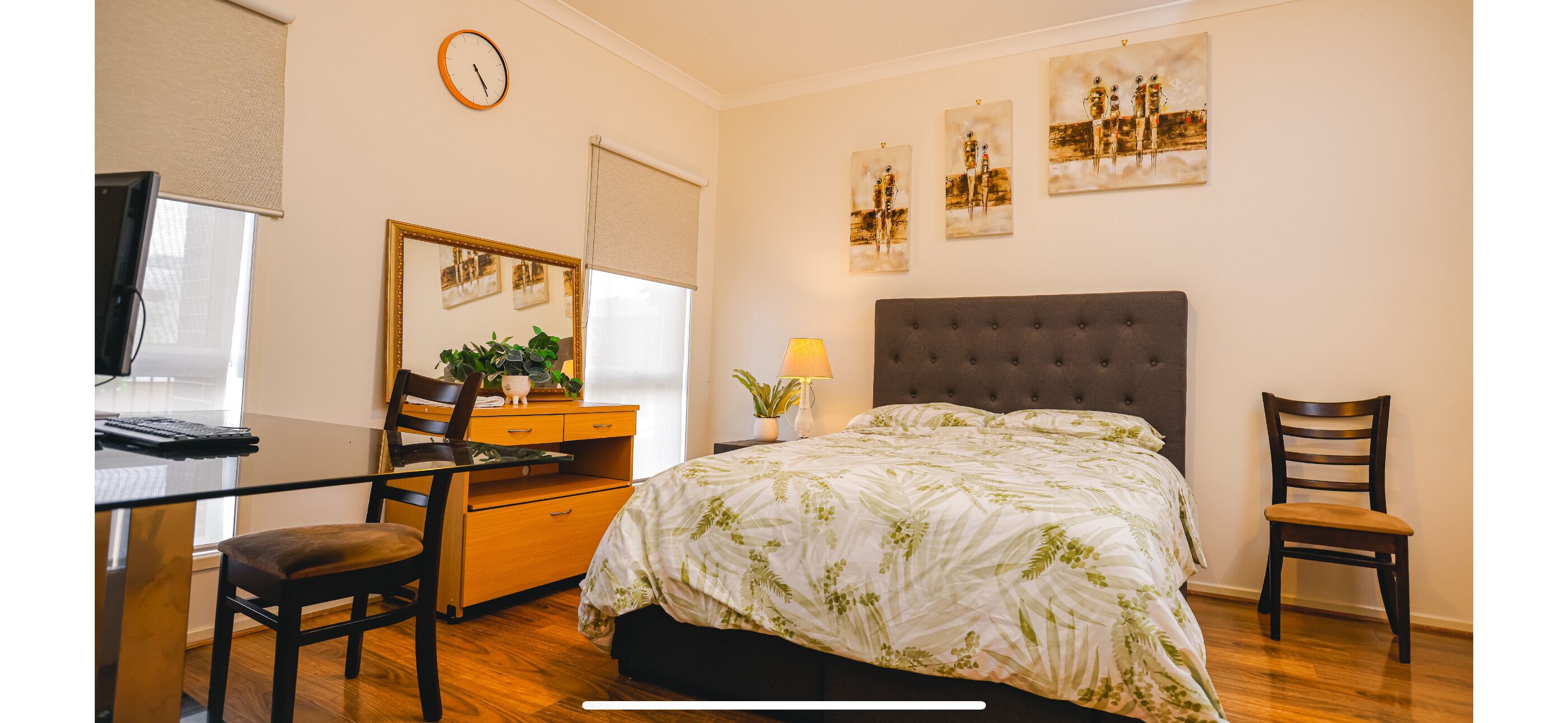 Un dormitorio con cama, escritorio, silla, cómoda, espejo y decoración en la pared.