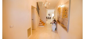 A hallway with a staircase, a chandelier, and a large abstract painting.