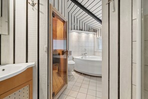 Et moderne badeværelse med hvid vask, toilet og badekar.