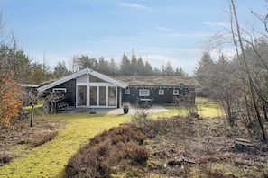 A modern building with a large glass entrance, a covered patio, and a grassy yard.
