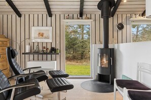 Un interior moderno con chimenea, zona de estar y vistas a través de un ventanal.