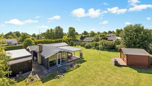 Een modern huis met een ruime glazen ruimte, een houten terras en een verzorgd gazon.