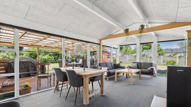 Een open woonruimte met een houten tafel, stoelen, banken en een televisie.