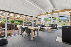 An open-plan living area with a wooden table, chairs, sofas, and a TV.