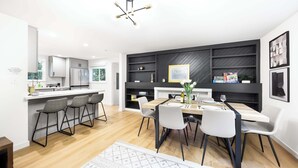 A modern kitchen with a dining area, featuring a central island, bar stools, and a chandelier. - Newly Modern 4BR2BA Rambler by Super Market (Shoreline)