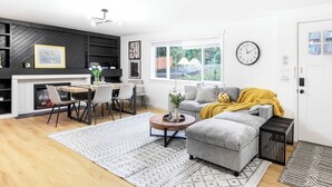 A modern living room with a grey sofa, a wooden coffee table, and a dining area with a white table and chairs. - Newly Modern 4BR2BA Rambler by Super Market (Shoreline)