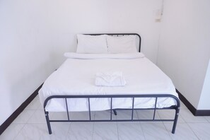 A single bed with white bedding and pillows, a metal frame, and a folded towel on the bed. - GO INN Patong Beach (Patong)