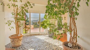 A spacious indoor area with a tiled floor, potted plants, and a large glass door leading outside. - Villa Giacinto di mare (Capoliveri)
