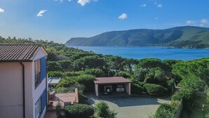 A coastal view with a building, a covered parking area, and a clear blue sky. - Villa Giacinto di mare (Capoliveri)
