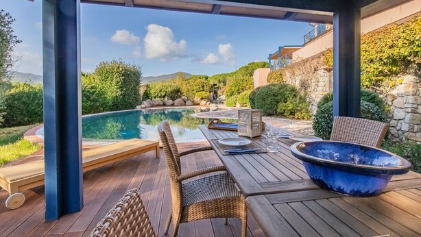 An outdoor pool area with a wooden deck, lounge chairs, and a hot tub. - Villa Giacinto di mare (Capoliveri)