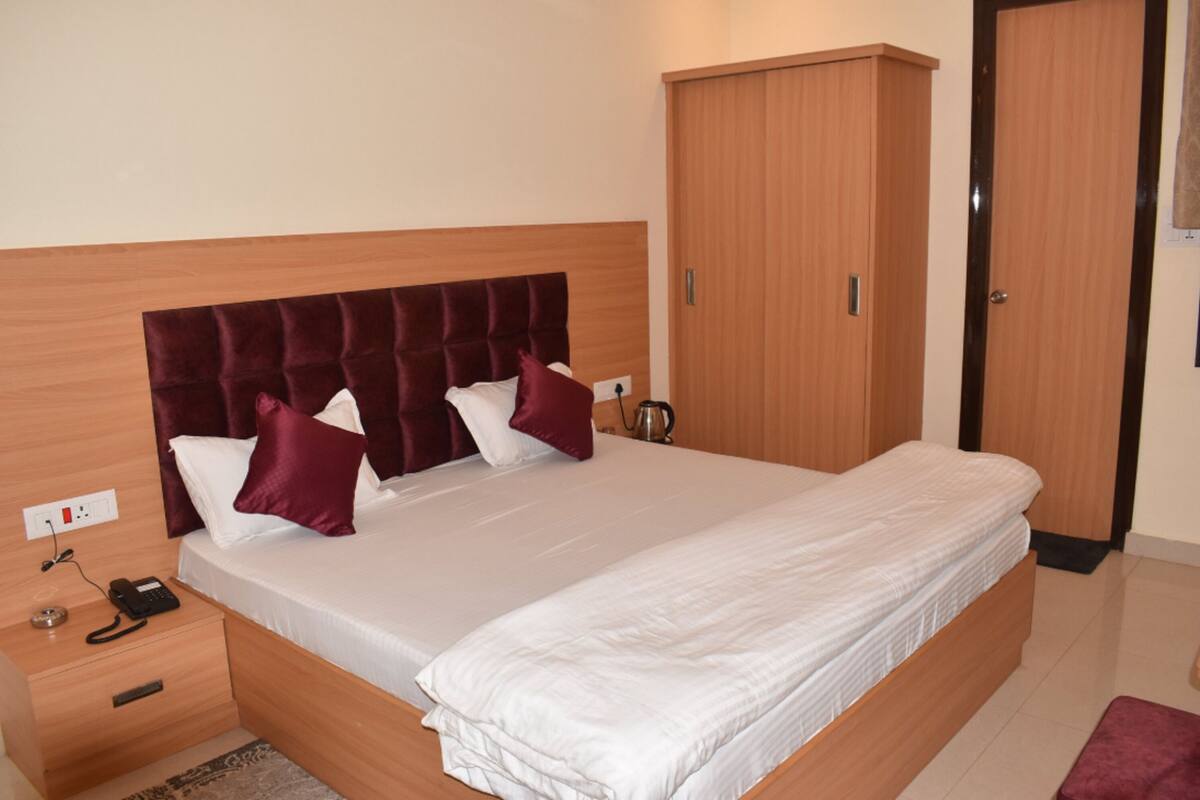 A neatly made bed with a wooden headboard, a bedside table with a phone, and a wardrobe.