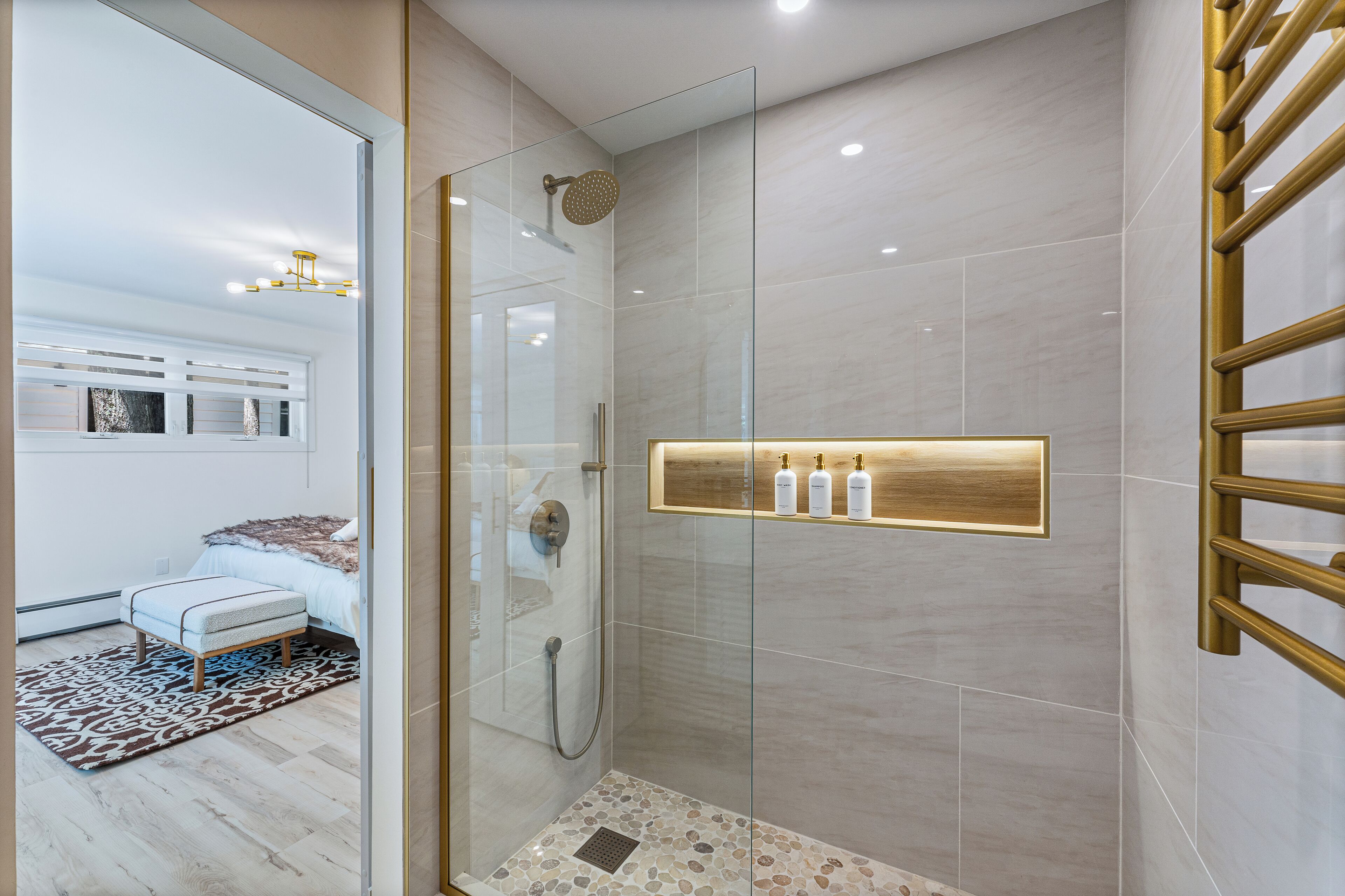 Ein modernes Badezimmer mit einer Duschkabine, einer Holzbank und einem Ablagebereich für Toilettenartikel.