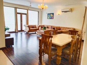 A spacious living area with a large sofa set, a dining table with chairs, and a chandelier. - Fortune Home Service Apartment 2Bhk,E28 Saket 2A (New Delhi)
