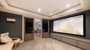 Een bioscoopzaal met een grote flatscreen televisie, een verstelbare fauteuil en een vloerbedekking.