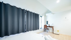 Ein Hotelzimmer mit Bett, Schreibtisch, Stuhl und Fenster.