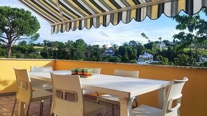A terrace with a striped awning, a white table, and chairs. - Italian Experience- Casa Nadia (Numana)