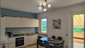 A modern kitchen with a dining area, wooden cabinets, a gas stove, and a dining table with chairs. - Italian Experience- Casa Nadia (Numana)